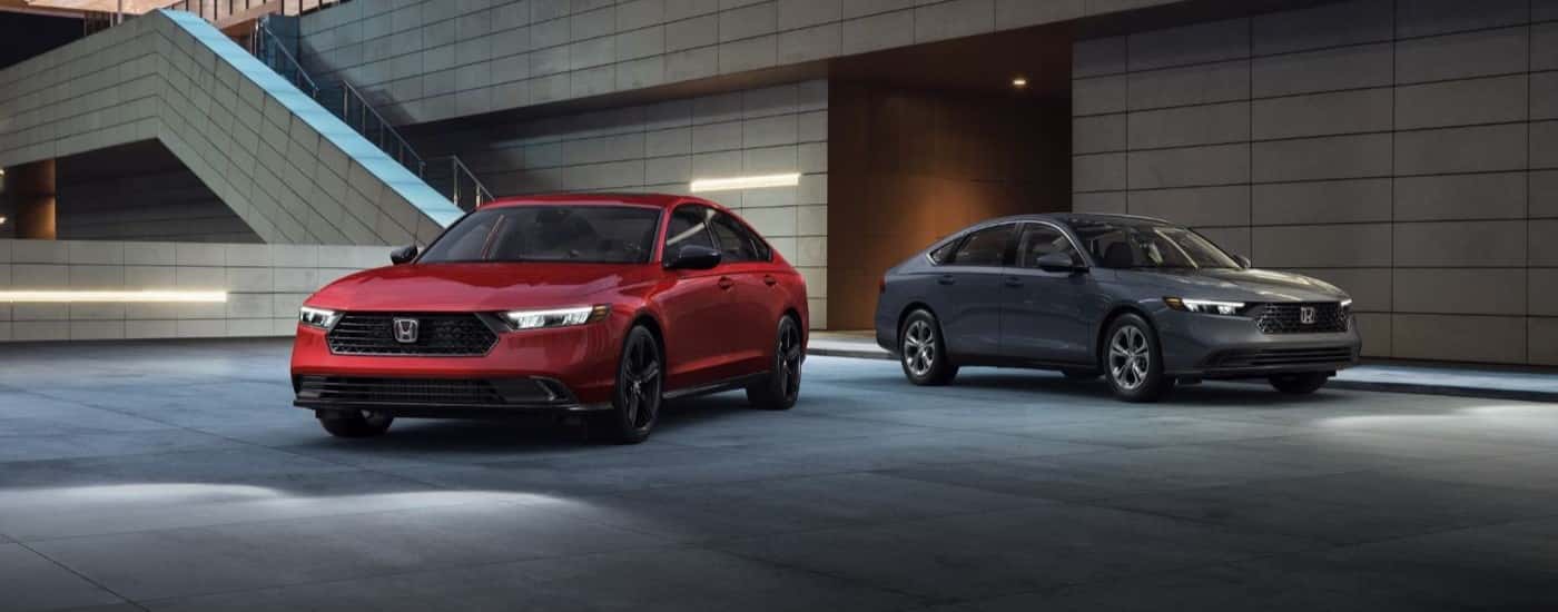 A red and a grey 2023 Honda Accord Hybrid for sale are shown from the front.