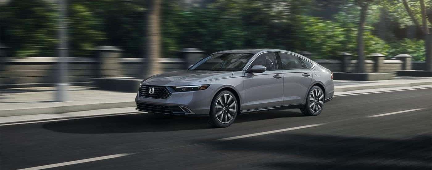 A gray 2025 Honda Accord Touring Hybrid driving on a city street.