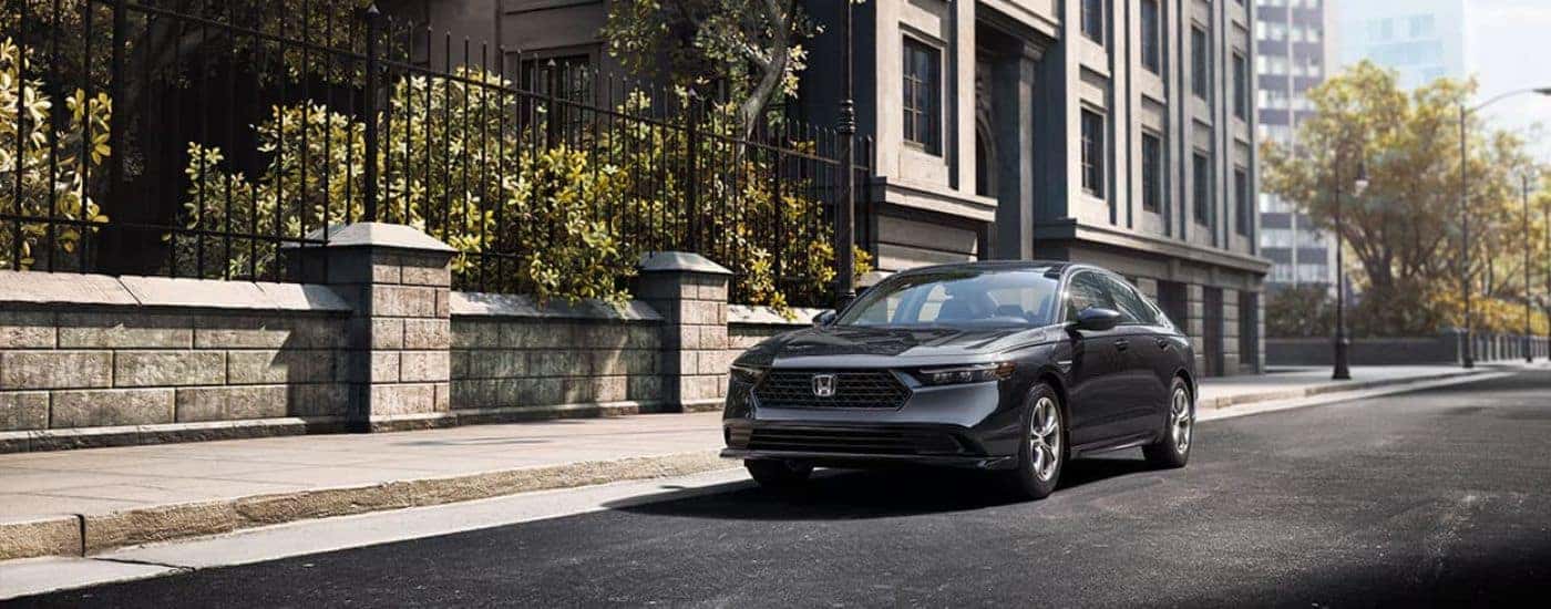 A grey 2024 Honda Accord for sale is parked on a city street.