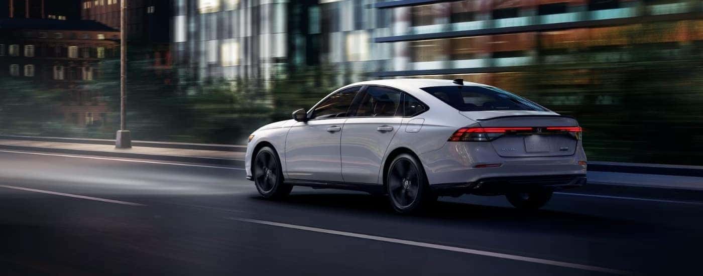 A white 2025 Honda Accord Sport-L is shown driving on a city street.