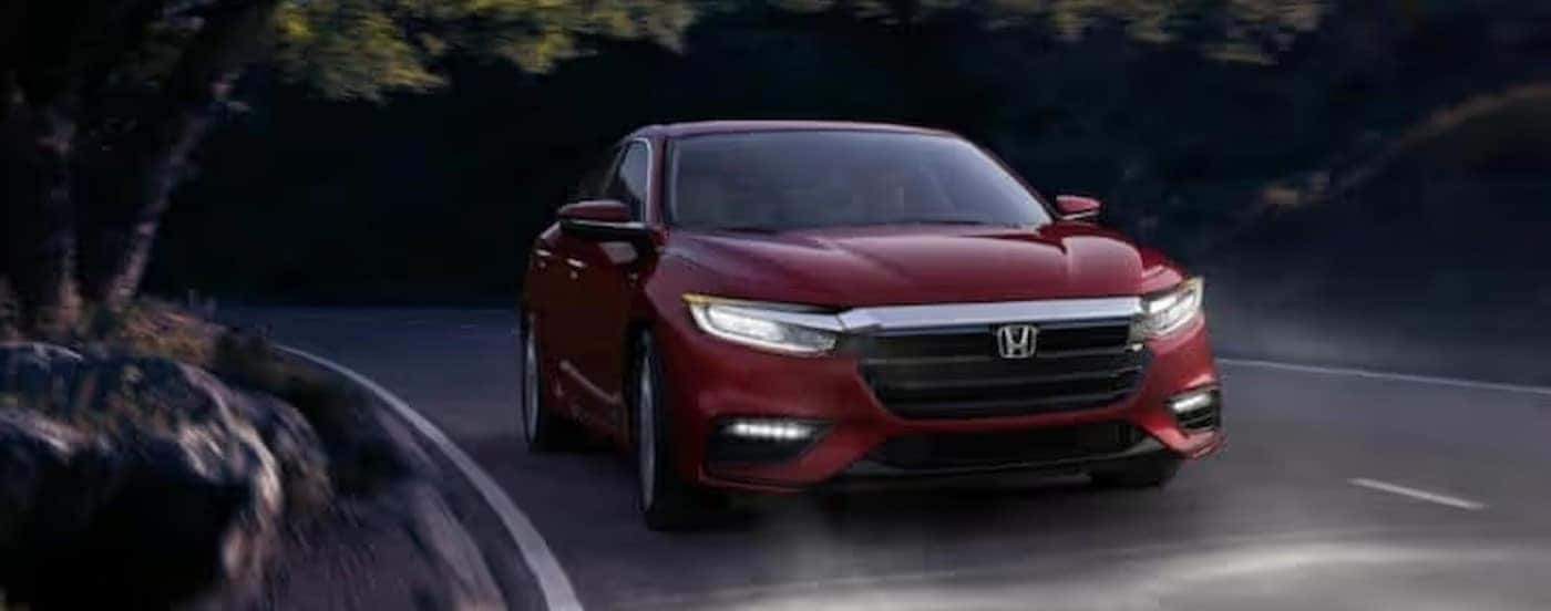 A red 2021 Honda Insight driving to a Honda dealer near Colleyville at night.