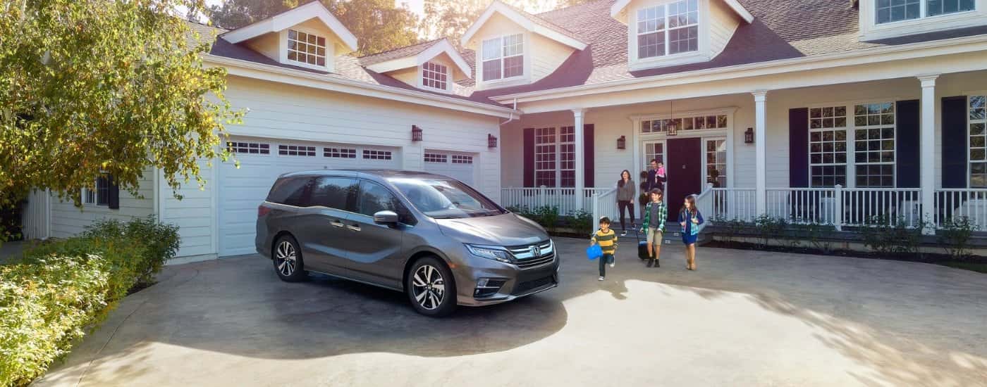 A silver 2024 Honda Odyssey is shown parked near a family.