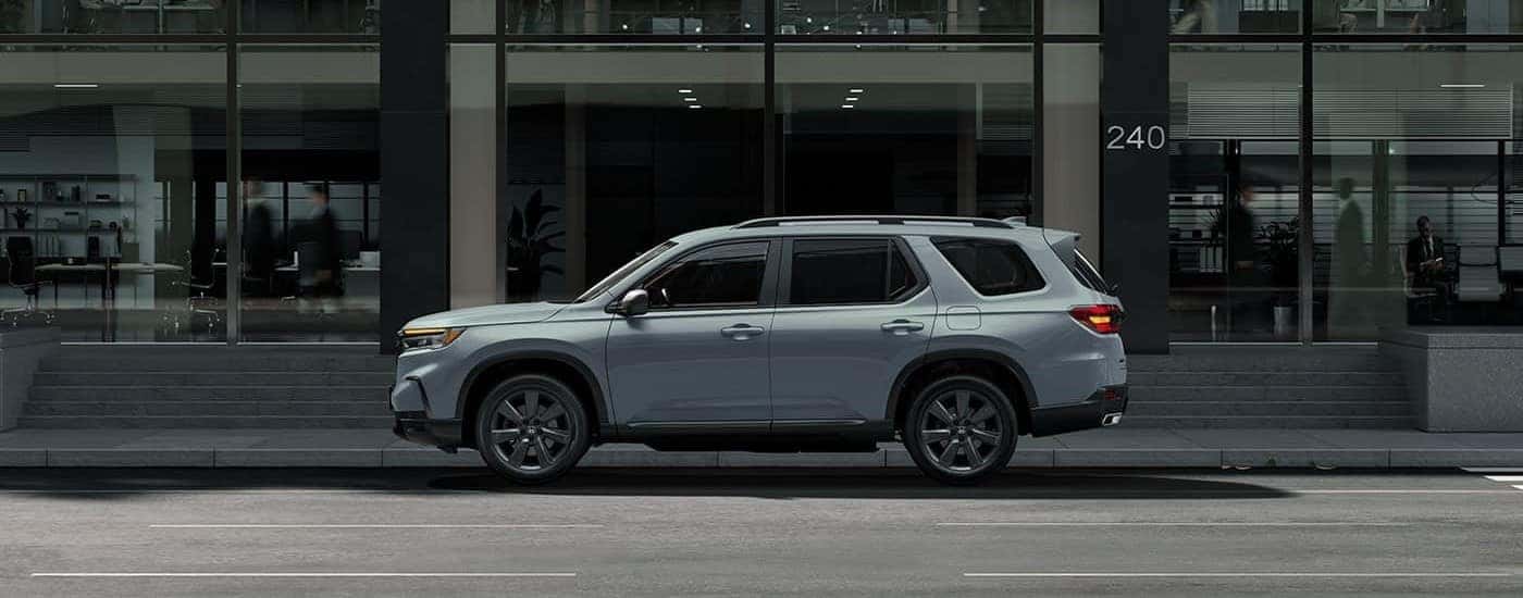 A gray 2023 Honda Pilot for sale near Irving is shown parked on a city street.