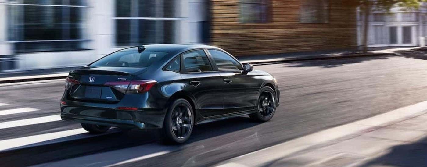 A black 2025 Honda Civic Sport driving in a city.
