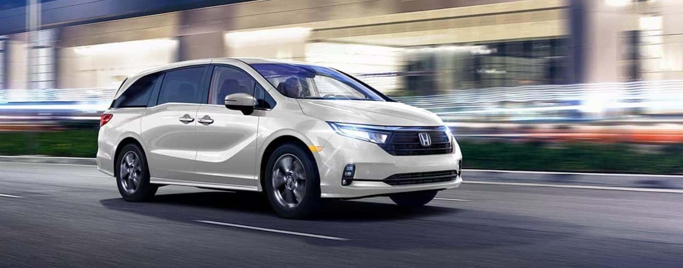 A white 2023 Honda Odyssey for sale near Grapevine driving on a city street.