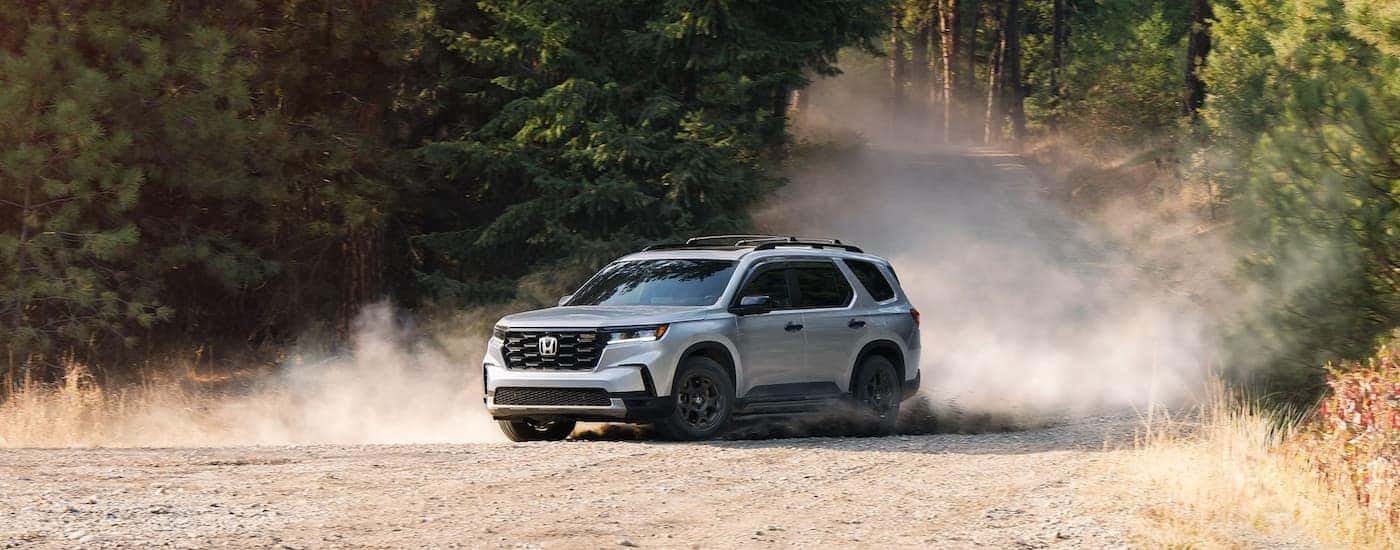 Silver 2025 Honda Pilot TrailSport for sale near Haslet driving down a dirt hill.