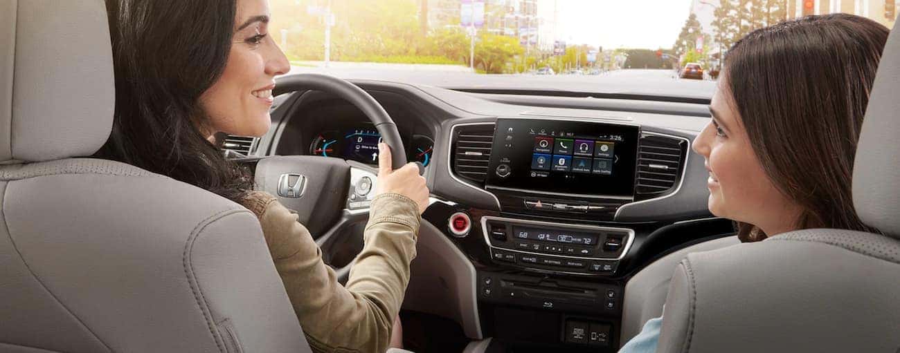 Two people driving in a 2021 Honda Pilot for sale near Newark.