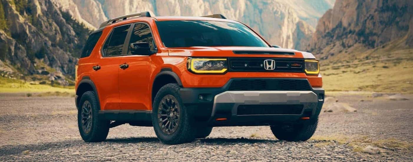 An orange 2026 Honda Passport TrailSport Elite parked off-road.