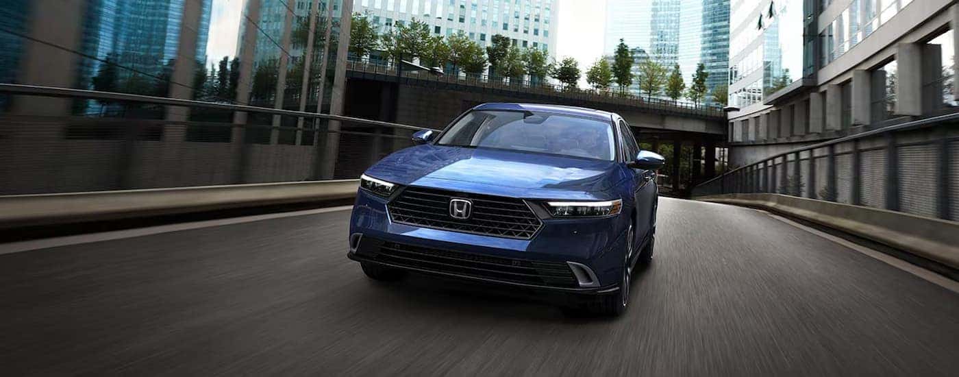 A blue 2025 Honda Accord driving down a city street