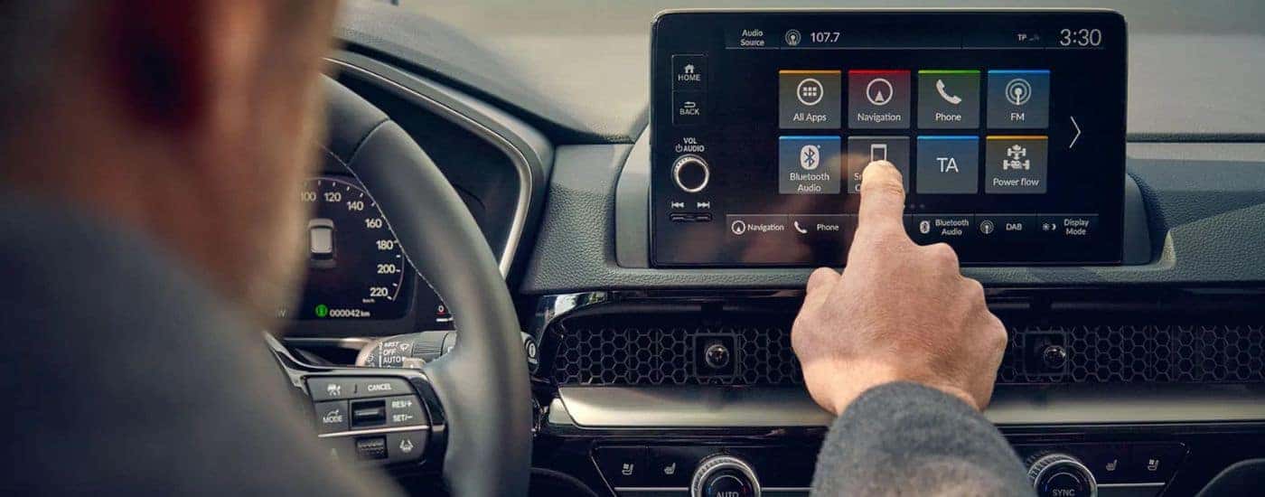 A man using the touch screen infotainment display in a 2025 Honda CR-V Hybrid for sale near Haslet
