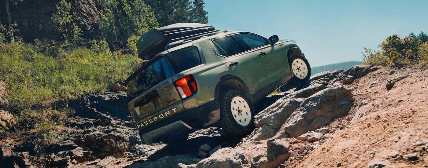 Rear of a green 2026 Honda Passport driving up a hill.