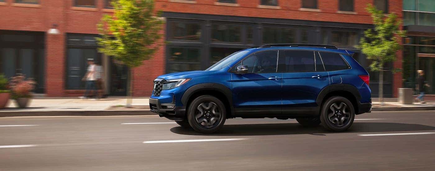 A blue 2023 Honda Passport Elite for sale near Grapevine driving in a city