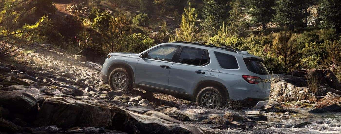 A gray 2023 Honda Pilot TrailSport off-roading on rocks