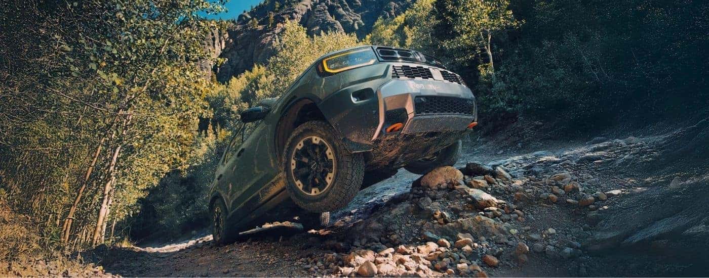 A green 2026 Honda Passport TrailSport off-roading on rocks