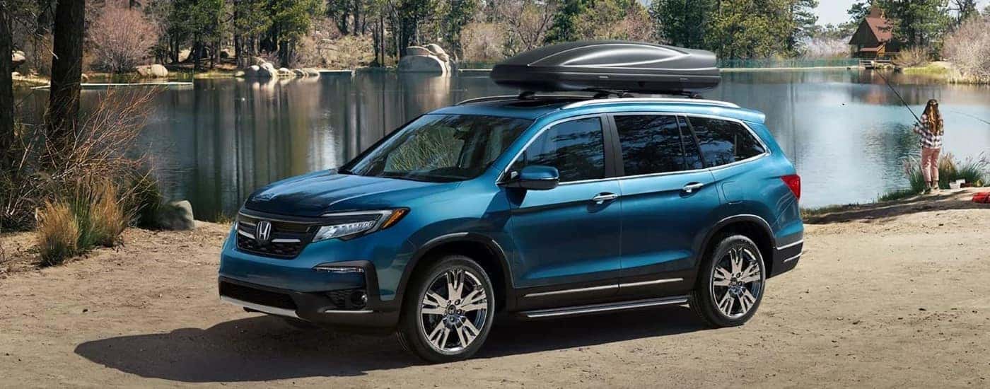 A blue used 2020 Honda Pilot Elite parked near a lake