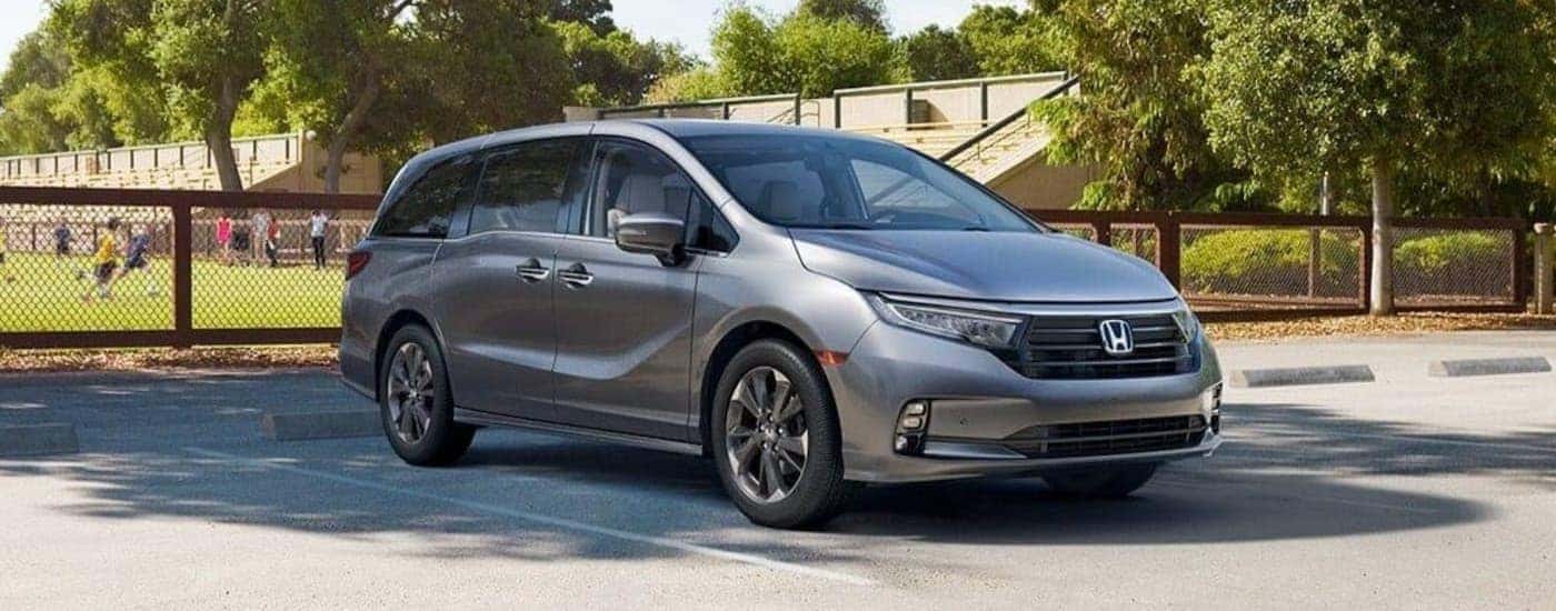 A silver 2024 Honda Odyssey parked near a soccer field.