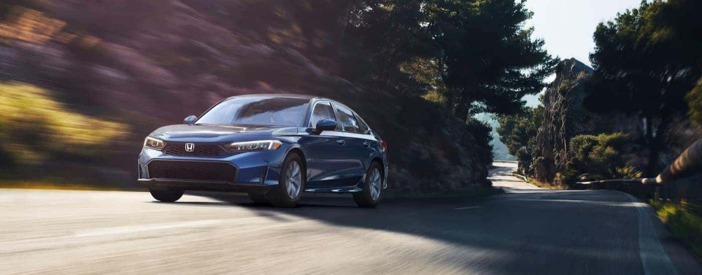 A blue 2025 Honda Civic driving on a highway.