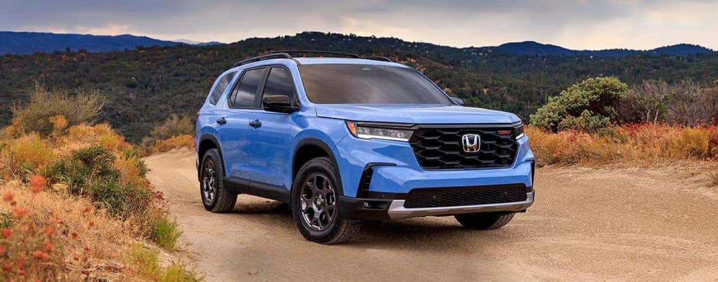 Blue 2026 Honda Pilot parked off-road.