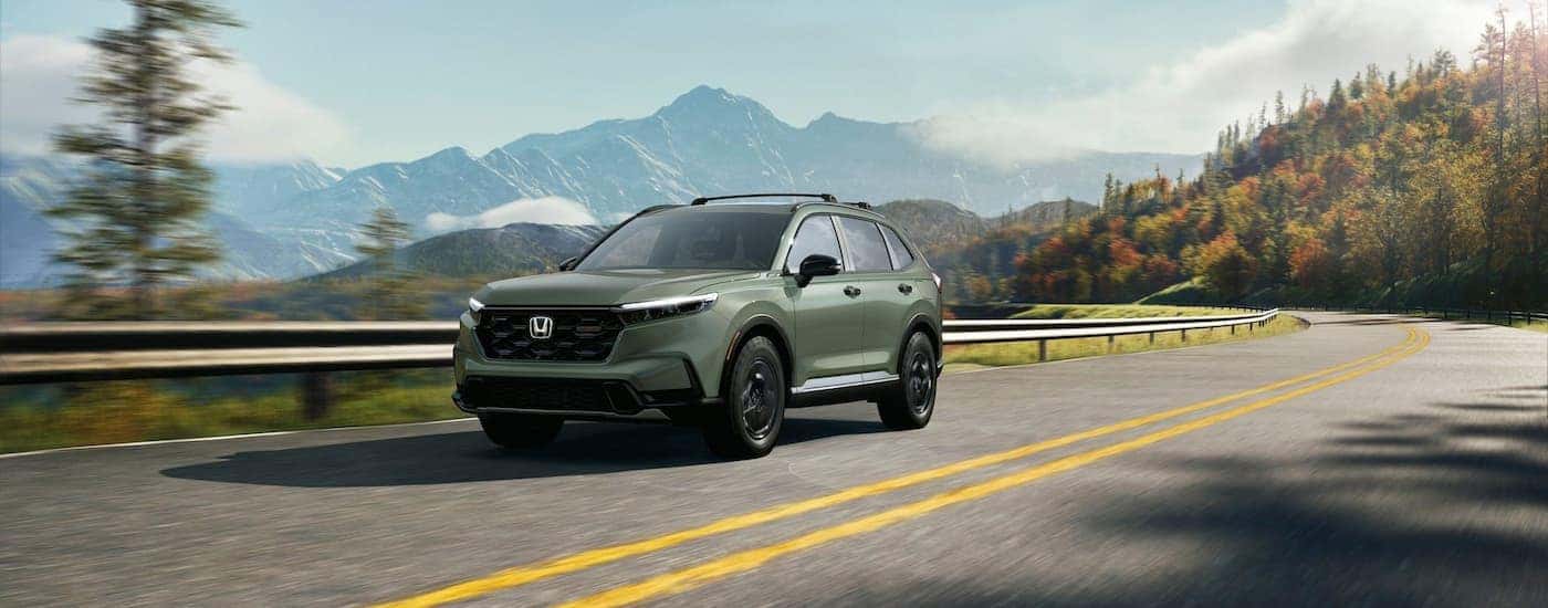 Green 2026 Honda CR-V driving around a bend.