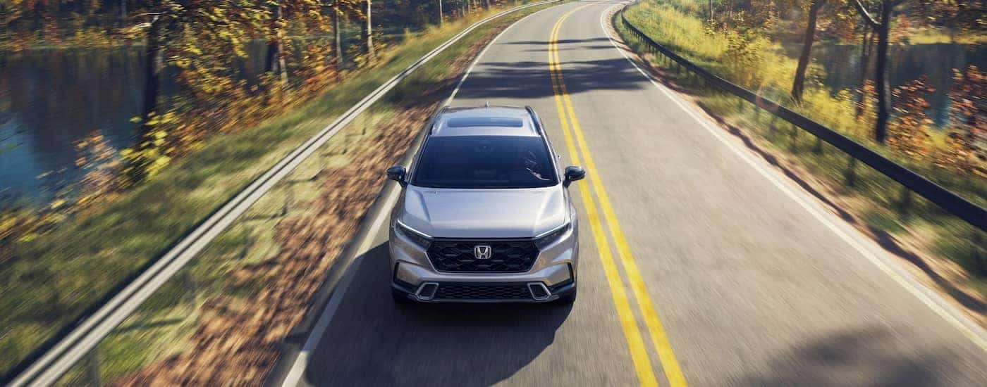 Front of a 2026 Honda CR-V Sport Touring driving down a road.