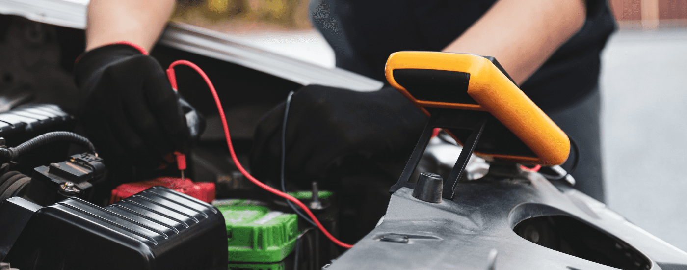 A mechanic testing the battery in a vehicle