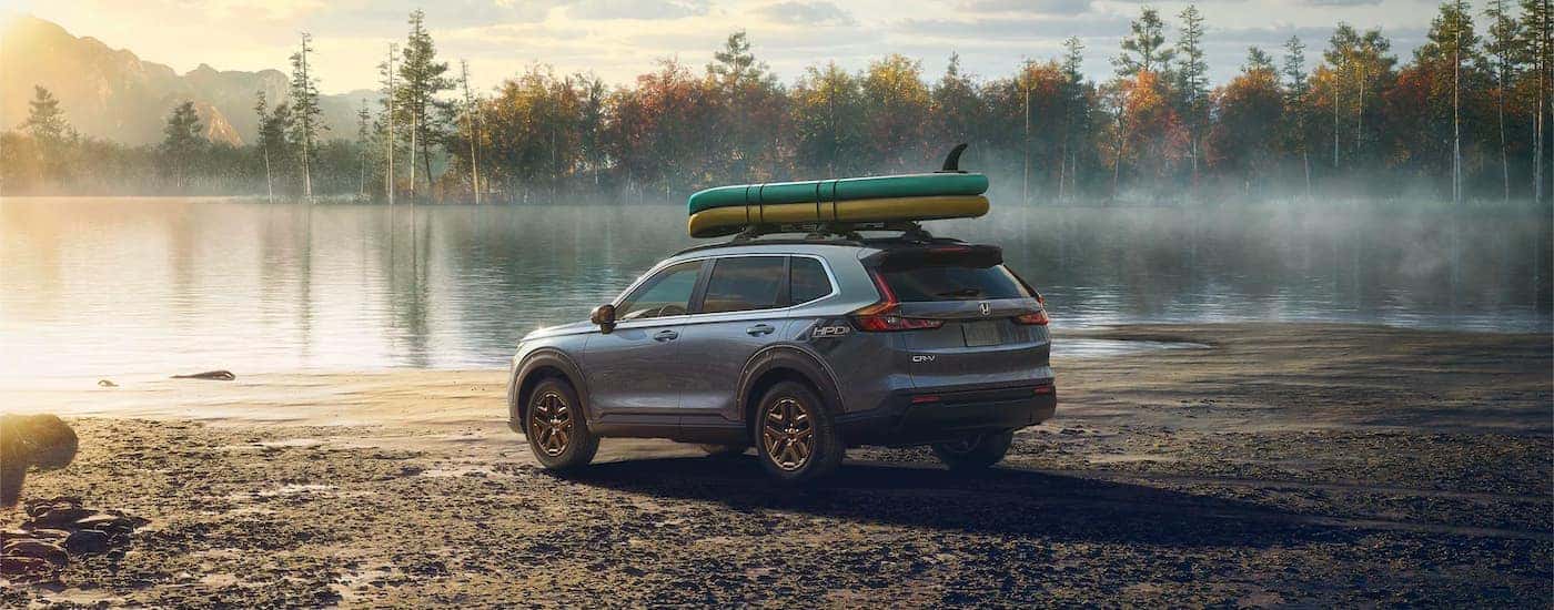 A gray 2024 Honda CR-V HPD EX parked off-road by a lake