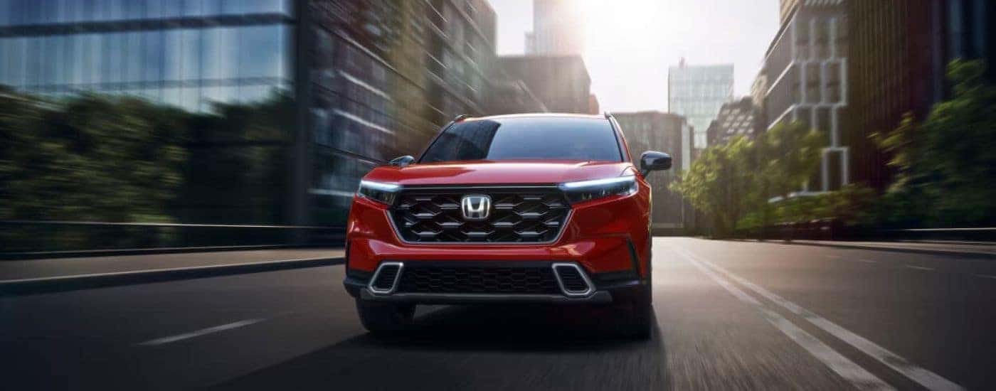 Red 2024 Honda CR-V driving on a city street
