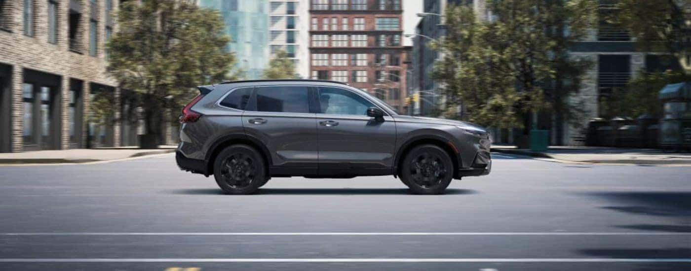A grey 2024 Honda CR-V driving on a city street.
