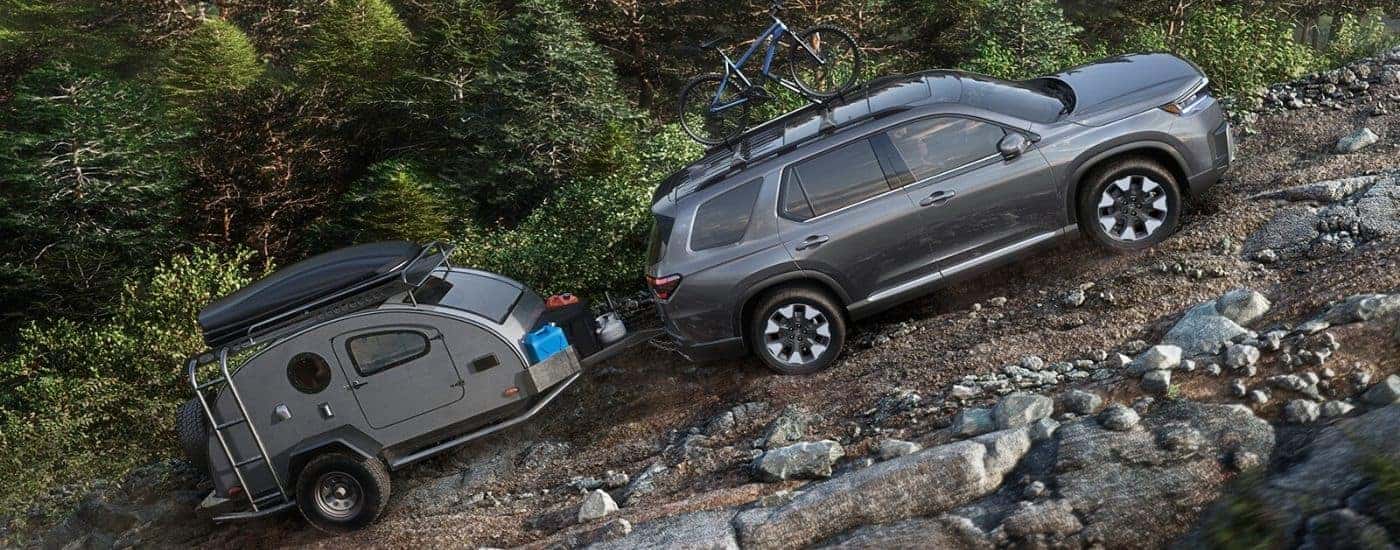 Grey 2026 Honda Pilot Elite towing a trailer off-road
