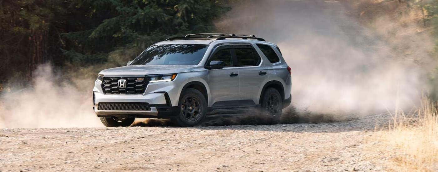 A silver 2025 Honda Pilot off-roading on a dirt road