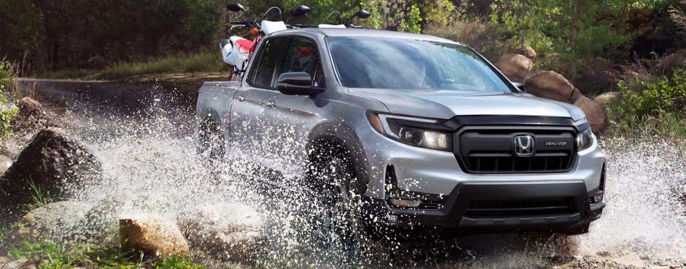 Silver 2026 Honda Ridgeline driving through a river.