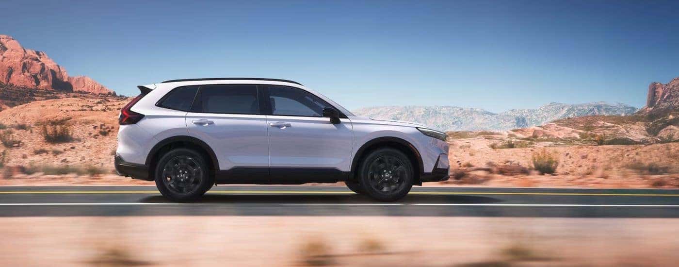 White 2026 Honda Cr-V Sport driving on a desert road.