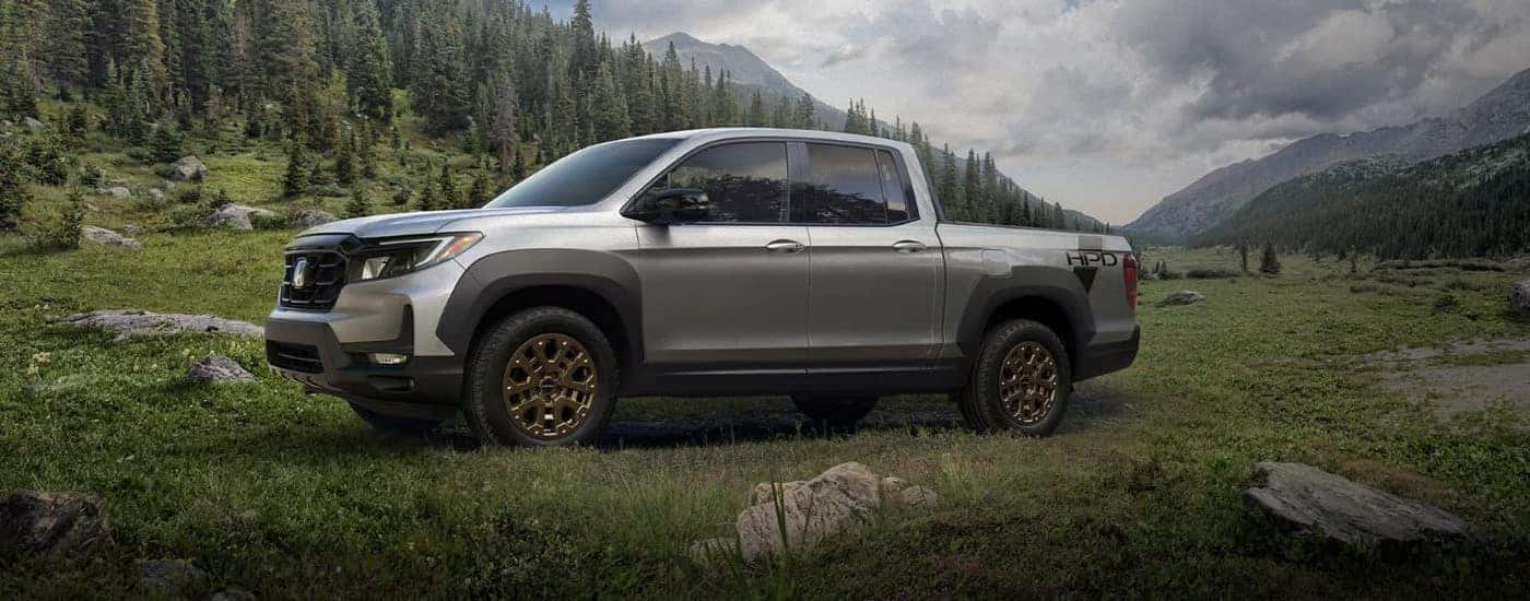 Grey 2023 Honda Ridgeline HPD from the side in a grassy field.