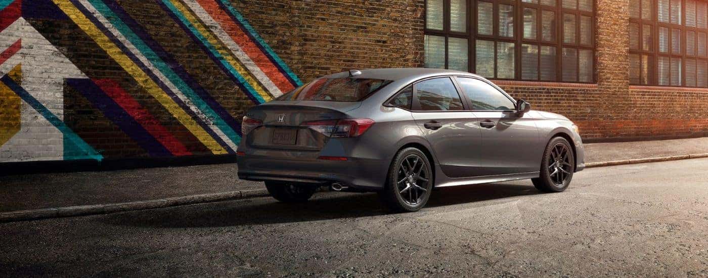 Grey 2026 Honda Civic rear parked in front of a painted brick building.