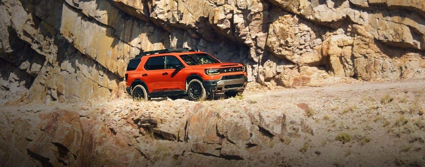 An orange 2026 Honda Passport Elite TrailSport driving a trail.