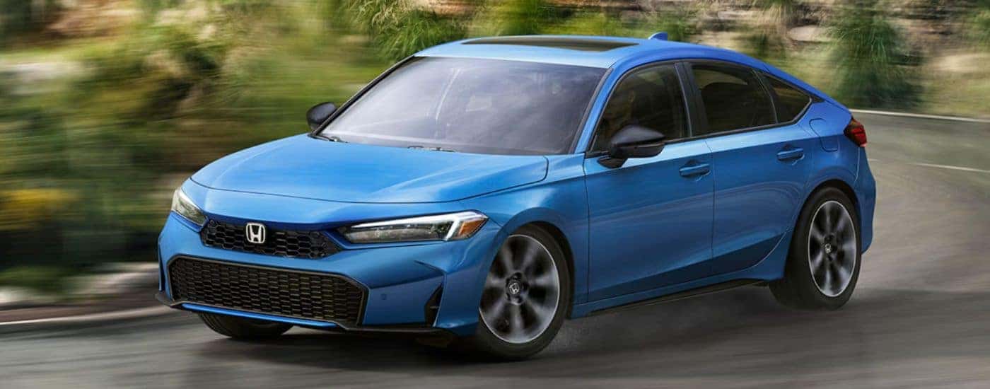 Blue 2026 Honda Civic Hatchback turning a corner on the road.