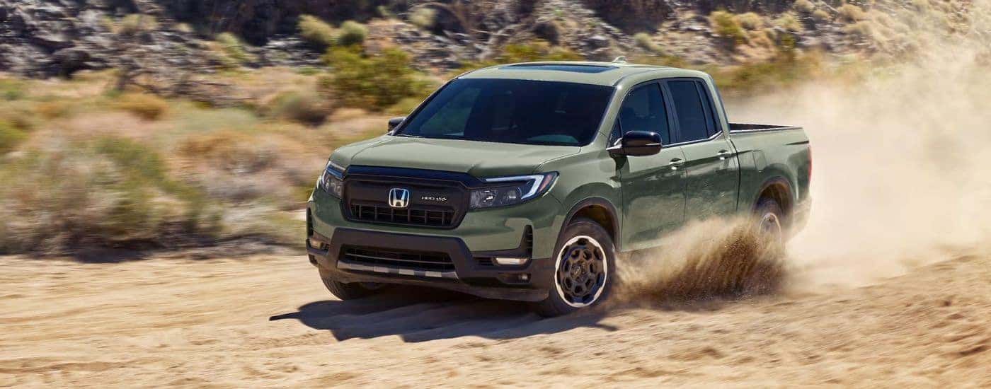 Green 2026 Honda Ridgeline TrailSport driving through sand in a desert.
