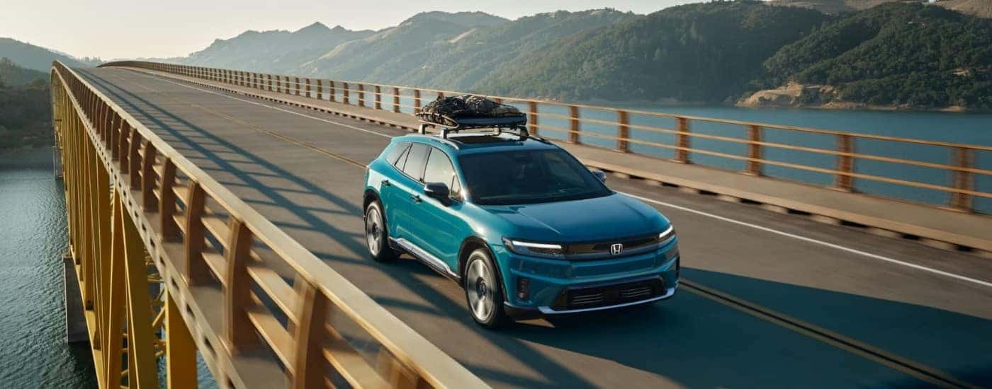 A blue 2024 Honda Prologue Elite driving over an ocean bridge.