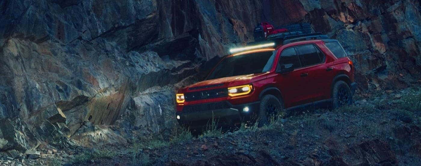 An orange 2026 Honda Passport TrailSport Elite off-roading at night.