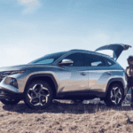 A silver Hyundai Tucson SUV with the trunk open, a hiker putting their equipment in the back.