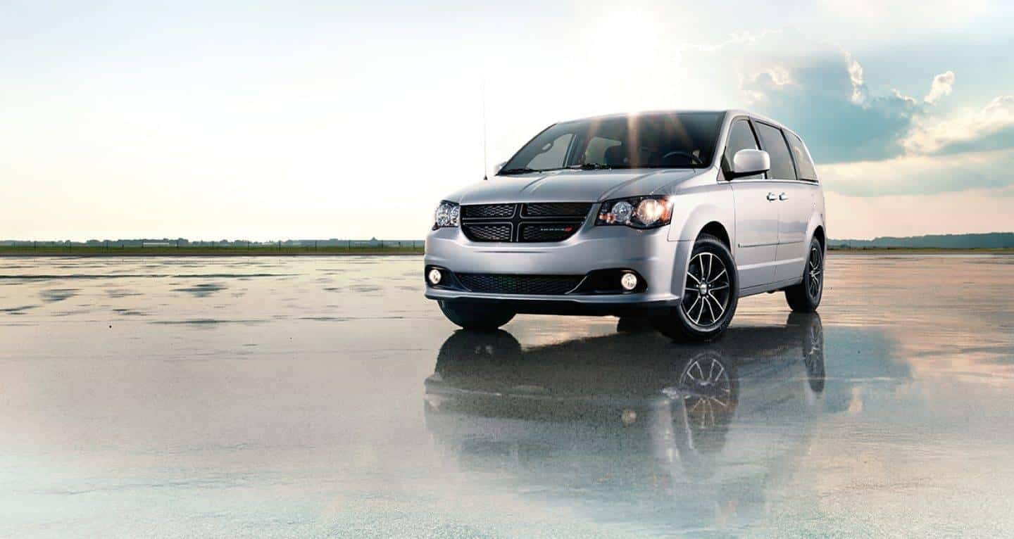 Schedule a Test Drive A silver Dodge Grand Caravan parked on wet pavement