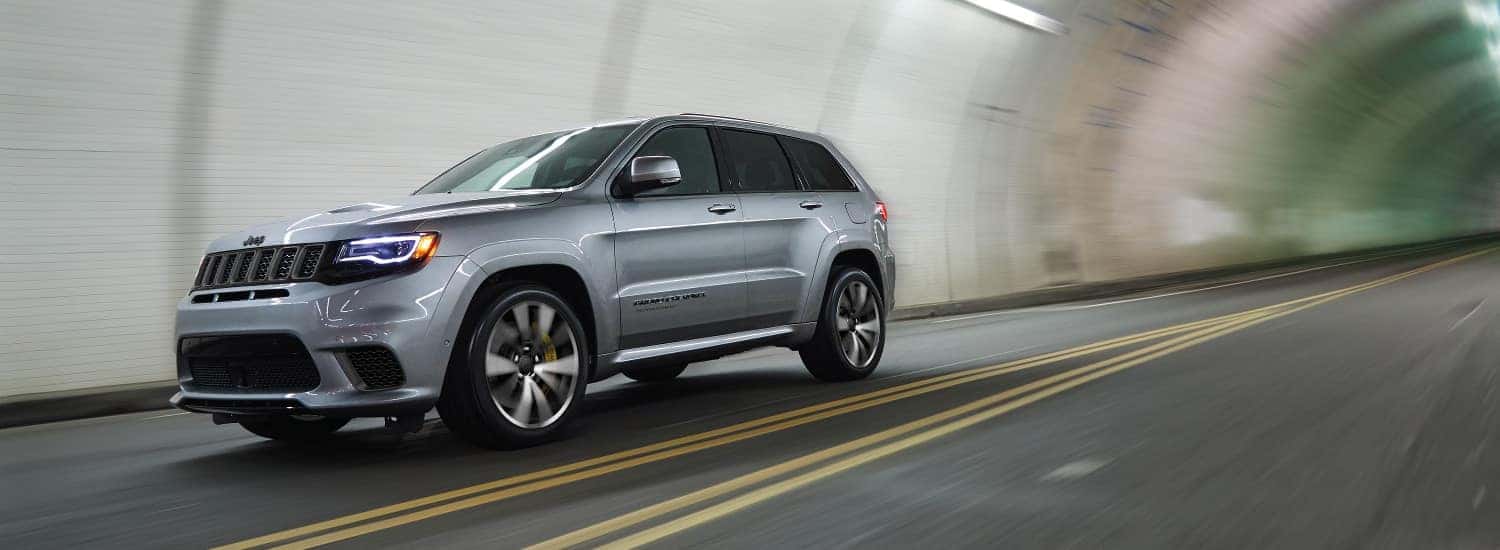 2018 Jeep Grand Cherokee Summit vs. SRT® vs. Trackhawk A silver 2018 Jeep Grand Cherokee driving through a tunnel
