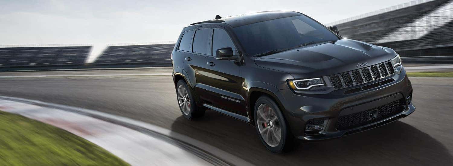 2018 Jeep Grand Cherokee Altitude vs. Limited vs. Sterling Edition A black 2018 Jeep Grand Cherokee driving on an open track