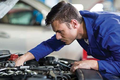 A service worker looking under a car hood