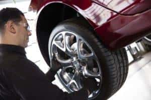 Man performing tire rotation on red car