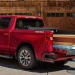 People taking wooden beams out of Red Chevy Silverado 1500