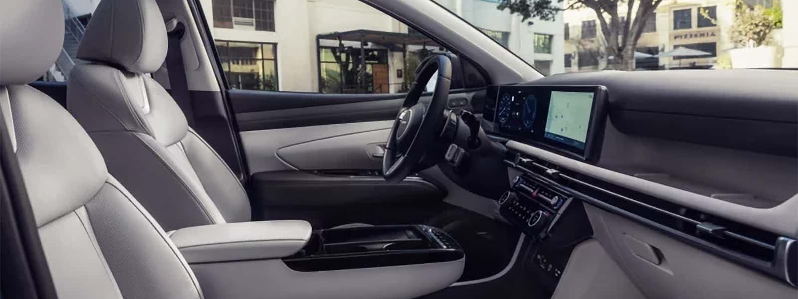 Front interior view of the Hyundai Tucson Hybrid showing modern dashboard design, center console, and light-colored seating.