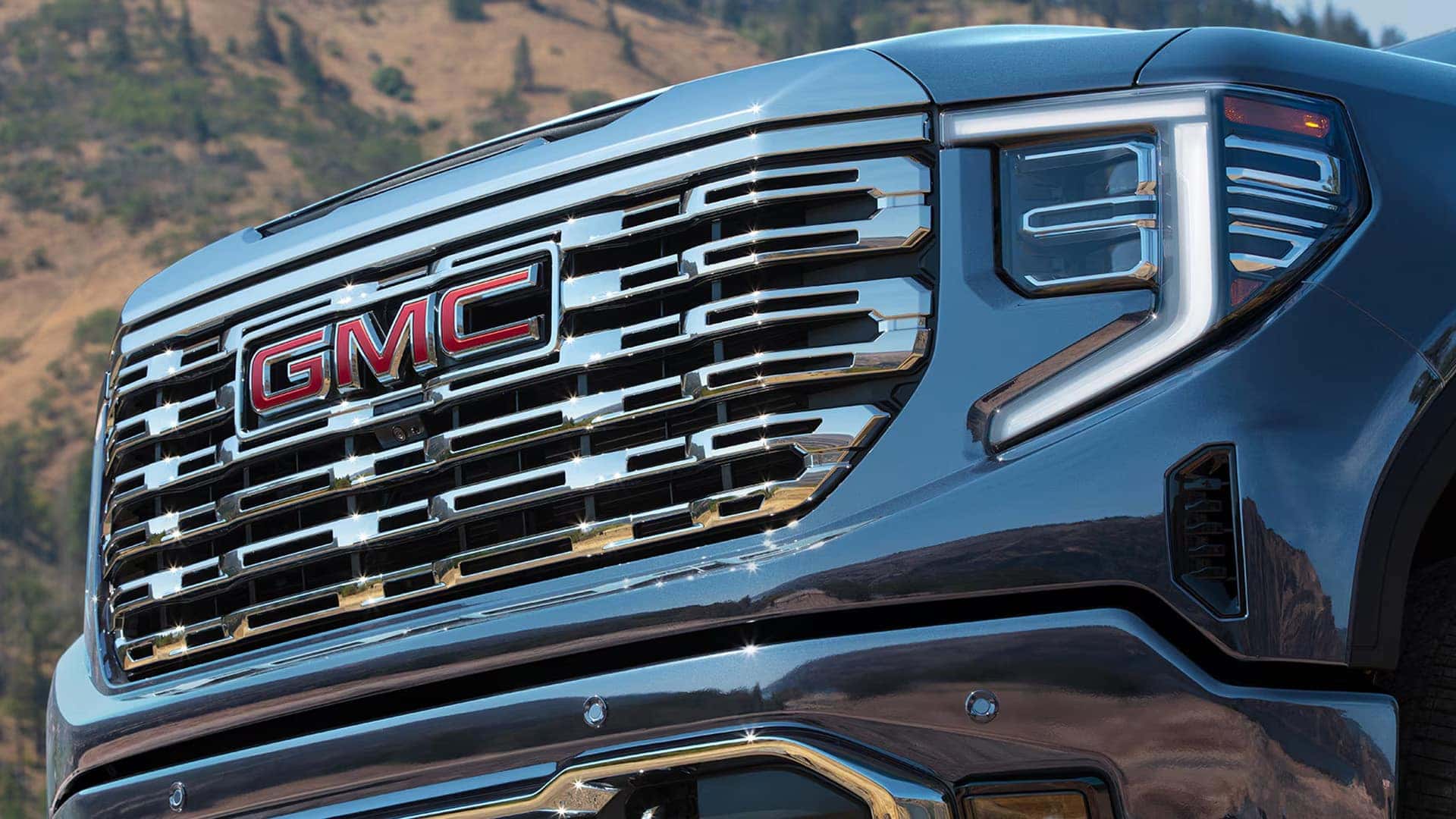 Close-up of the 2026 GMC Sierra 1500 front grille and LED headlight, showcasing GMC badge and refined exterior styling.