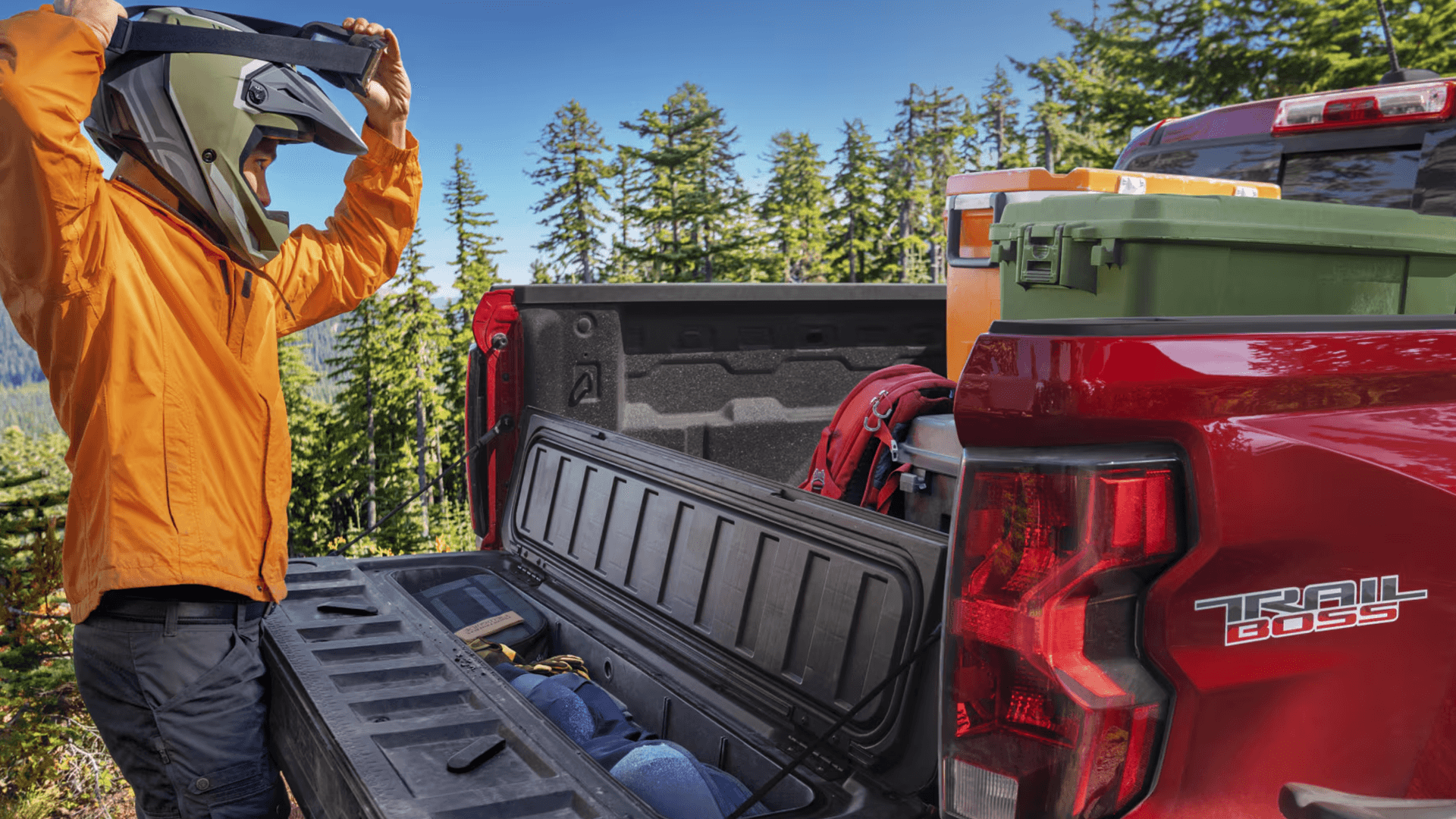 Person adjusting helmet beside Chevy Colorado Trail Boss truck bed