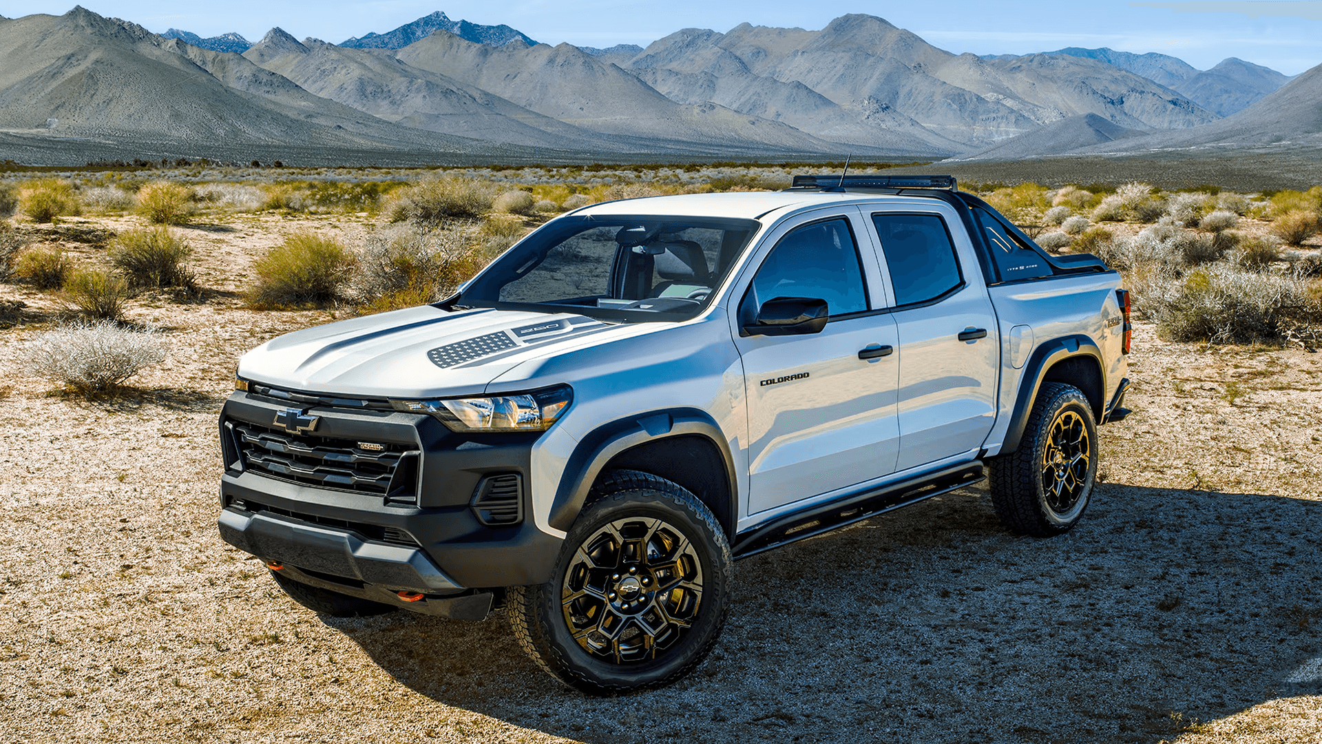 White Chevy Colorado Trail Boss parked in a desert landscape with mountains in the background